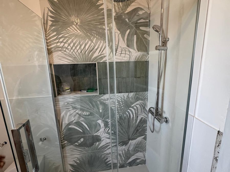 Bagno rifatto con box doccia in cristallo e parete decorata
